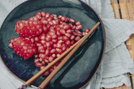 Peace of Pomegranate fruit with lots of seeds, a red exotic fruit on a grey background. Chopped pomegranate. pomegranate seeds are ready for eating.の写真素材