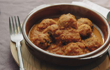 Rustic plate of meatballs in tomato sauce set on a tablecloth.の写真素材