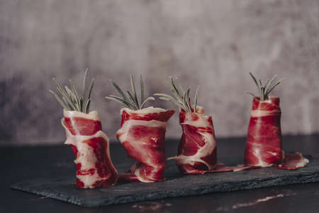Plate of delicious Iberian ham on a wooden table background. Appetizing slices Iberian ham. Acorn-fed Iberico Ham. Pata negra, spectacular vision of sliced ham. Typical spanish food.の写真素材