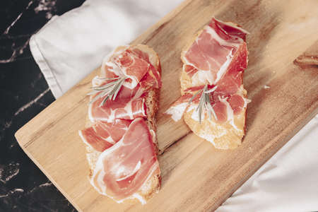 Plate of delicious Iberian ham on a wooden table background. Appetizing slices Iberian ham. Acorn-fed Iberico Ham. Pata negra, spectacular vision of sliced ham. Typical spanish food.の写真素材