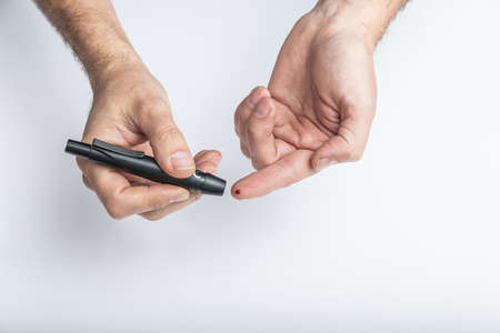 close up of hands using lancet on finger to check blood sugar level by Glucose meter, Healthcare Medical and Check up, Medicine, diabetes, glycemia, health care and people concept.の写真素材