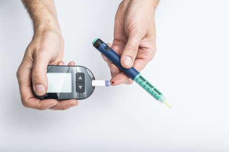 close up of hands using lancet on finger to check blood sugar level by Glucose meter, Healthcare Medical and Check up, Medicine, diabetes, glycemia, health care and people concept.の写真素材