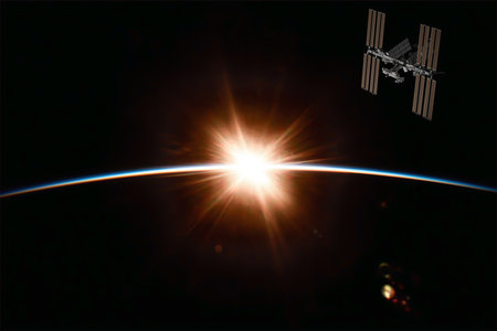 The International Space Station over the planet Earth at sunrise over the horizon.