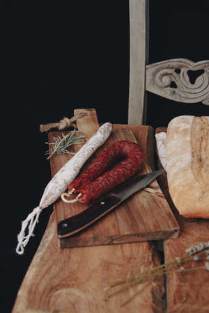 Fuets Catalan dry sausages. Set of spanish sausages and dry cured meat chistorra, chorizo, salchichon, fuet, olives, rosemary, chili peppers on a wooden background. top view.の写真素材
