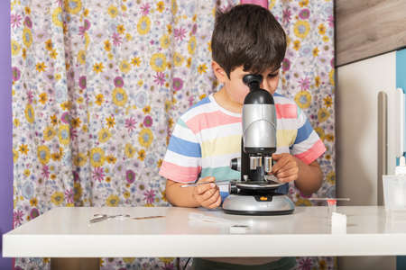 Little child caucasian boy looking through microscope in school.の写真素材