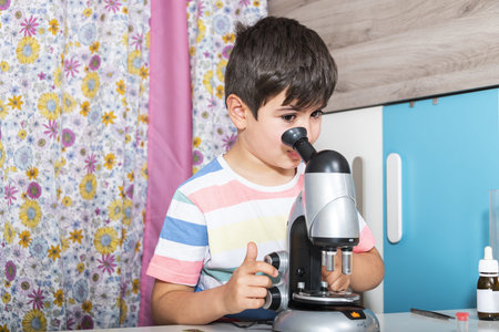 Caucasian Boy examining preparation under the microscope.