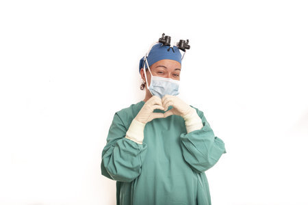 Young blonde surgeon doctor woman over isolated background smiling in love showing heart symbol and...