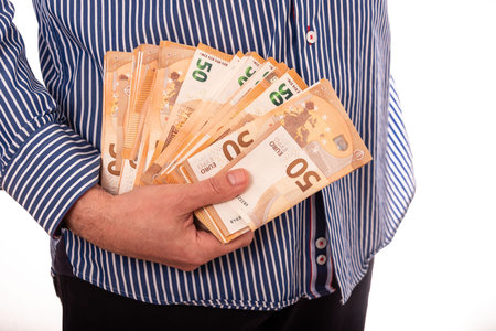 Close up hand of a businessman holding banknote into pocket. It represents very profitable investment. The exchange of currencies with good returns. And money to buy debt securities increase revenue.の写真素材