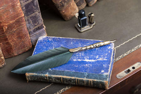 Compilation of old books on wooden desk and writing pen.の写真素材