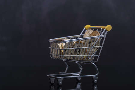 Side view of bitcoin and shopping cart on black background. Buying or selling the cryptocurrency concept. Virtual money, cryptocurrency. E-commerce concept.の写真素材