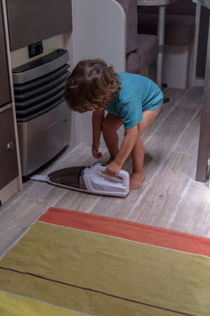 Cute and diligent baby cleans the caravan with a vacuum cleaner.の写真素材