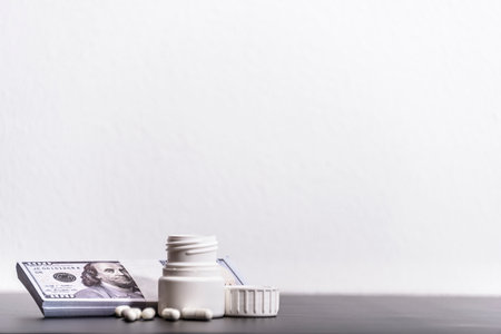 Dollars and white pills on a black background from up close.の写真素材