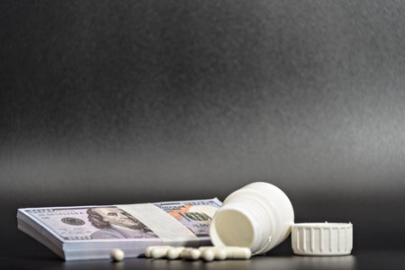 Dollars and white pills on a black background from up close.の写真素材