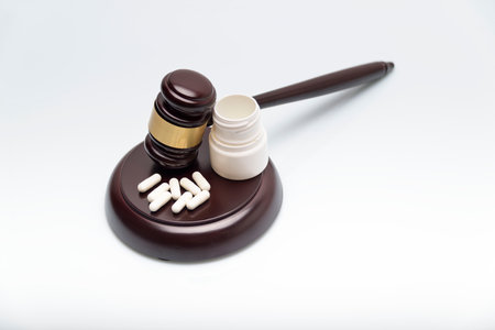 Medicine and law. Pills capsules and judge gavel isolated on white background.の写真素材