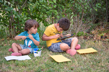 Two students lying in a park with their backpacks, one of them writing in a notebook.の写真素材
