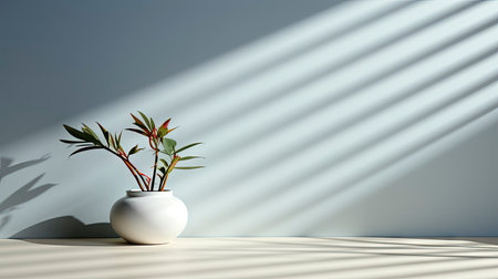 Minimalist interior with potted palm, striped sunlight, and elegant wooden vases on muted blue wallの素材