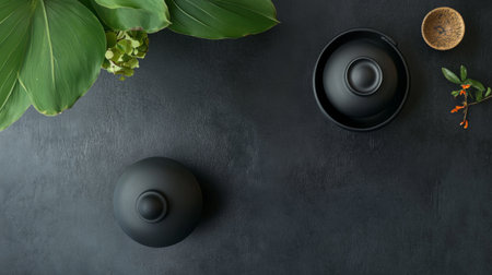 A minimalist black tea set arranged on a dark background with green leaves, creating a sleek and tranquil composition.の素材