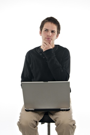 teenager sitting on stool with laptop deep in thought on white backgroundの写真素材