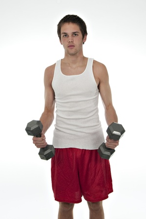 fit teenager in t-shirt and shorts holding weights in his hands on a white backgroundの写真素材
