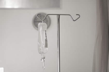 IV bag hanging on a metal pole in the hospital roomの写真素材