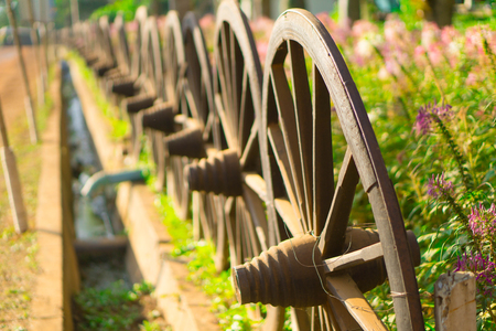 Old wooden wheel on hay, flower gardenの写真素材