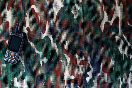 Mobile phone on military camouflage net backgroundの写真素材