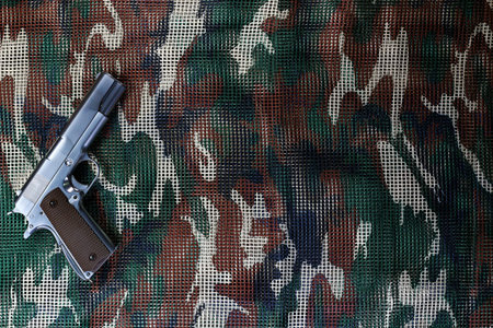 Handgun on military camouflage net background