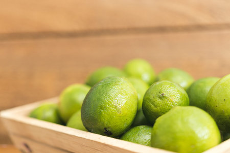 Fresh green lemons on wooden bottom