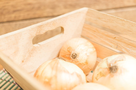 onions in a wooden box on a wooden backgroundの写真素材
