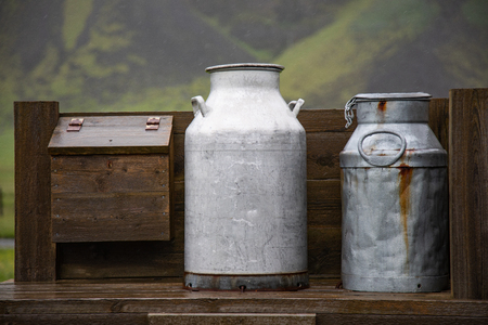 Old milk cans sitting on a wooden structureの写真素材