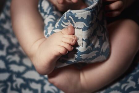 Crop baby playing with ornamental blanketの写真素材