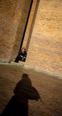 A person sitting in a sun lit space with a shadow.のeditorial素材