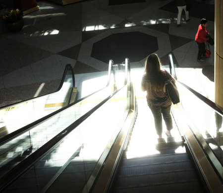 Woman on an escalator, strongly lighted.