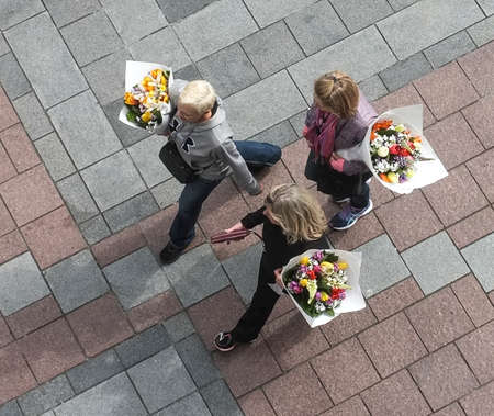 Overhead view of three woman carrying large bouquets of flowers.の写真素材