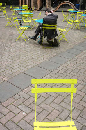 A thinking man outdoors in yellow chairs.の写真素材