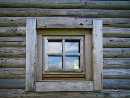 A small wooden square window on a log cabin. The photo was taken at the children's playgroundの写真素材