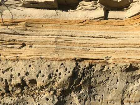 Close-up of layered sandstone showing horizontal striations and varying shades of tan, brown, and beige, revealing natural sedimentary rock patterns formed over time.の写真素材