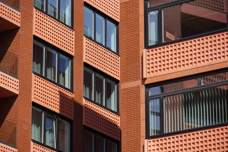 Modern brick apartment building with large windows reflecting sunlight in a vibrant urban setting