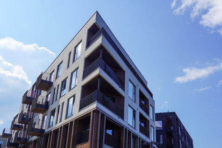 Modern residential building with balconies and clear blue sky in a sunny urban areaの写真素材