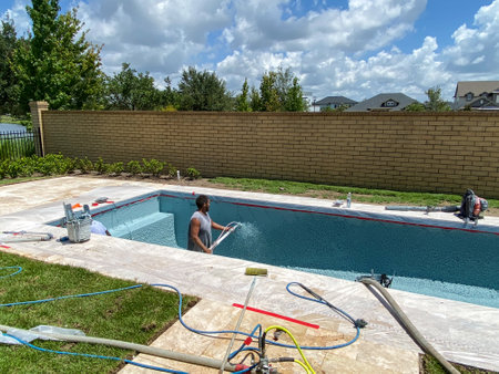 Orlando, FL/USA-7/7/20: Workers from a pool finishing company spraying plaster finish on the interior of a swimming pool in Florida.のeditorial素材