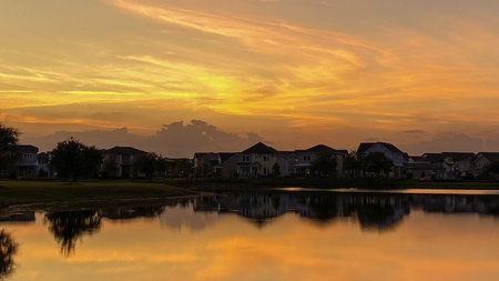 Beautiful pink, orange and blue sunset reflecting on a lake in a suburban neighborhood.