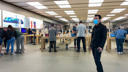 Orlando, FL USA - February 5, 2021:  Apple employees waiting on customers with plexiglass sheilds between while wearing face masks due to the coronavirus pandemic.のeditorial素材
