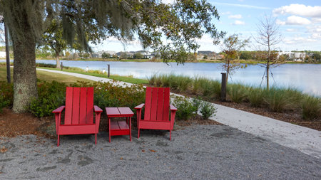 Orlando, FL USA -  January 7, 2020: Two chairs sitting in a park by a lake in Laurete Park in Lake Nona, Orlando, FL on a beautiful sunny day.のeditorial素材