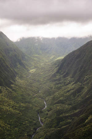 A river winding down through the cloud covered mountains の写真素材