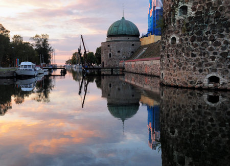 Corner Towers Mirroring In The Moat Of Vadstena Castle At Dusk On A Sunny Summer Day With Some Clouds In The Skyのeditorial素材