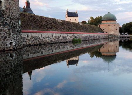 Vadstena Castle Mirroring In Its Moat At Dusk On A Sunny Summer Day With Some Clouds In The Skyのeditorial素材