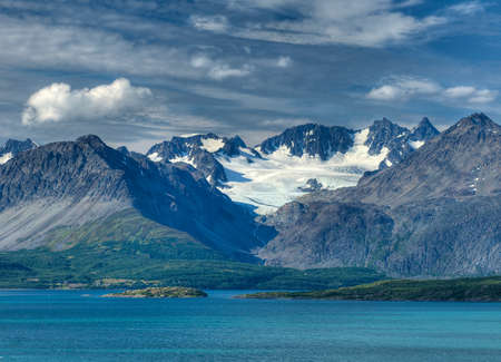 View To The Glacier Covered Lyngen Alps Mountains At Lyngenfjord On A Sunny Summer Day With A Clear Blue Sky And A Few Cloudsの写真素材
