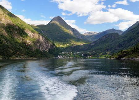 View From A Boat To Geiranger Village In The Geirangerfjord On A Sunny Summer Day With A Clear Blue Sky And A Few Cloudsの写真素材