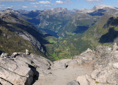 View From Dalsnibba Lookout To The Large Mountains Of Geirangerfjord On A Sunny Summer Day With A Clear Blue Sky And A Few Cloudsの写真素材