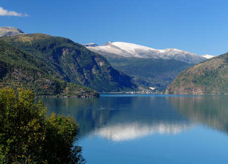 View From Urnes To The Lustrafjord And A Village On A Sunny Summer Day With A Clear Blue Sky And A Few Cloudsの写真素材